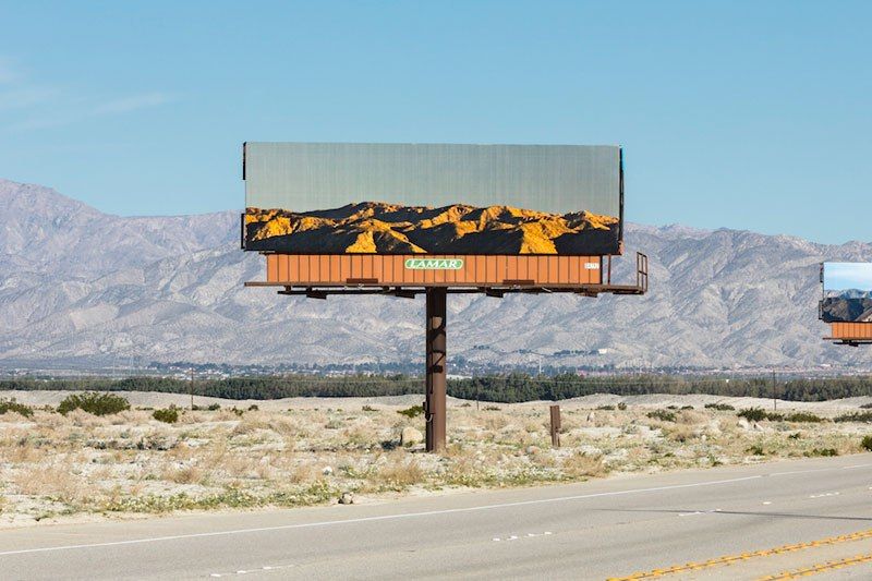 Художник заклеивает билборды пейзажами, которые те перекрывают
