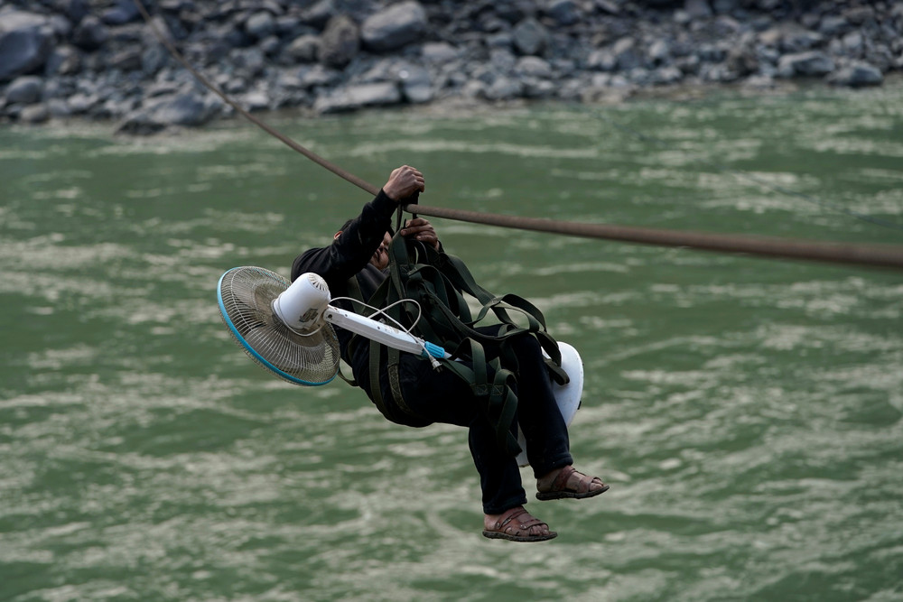 Жители китайской деревни используют стальной канат для переправы через реку