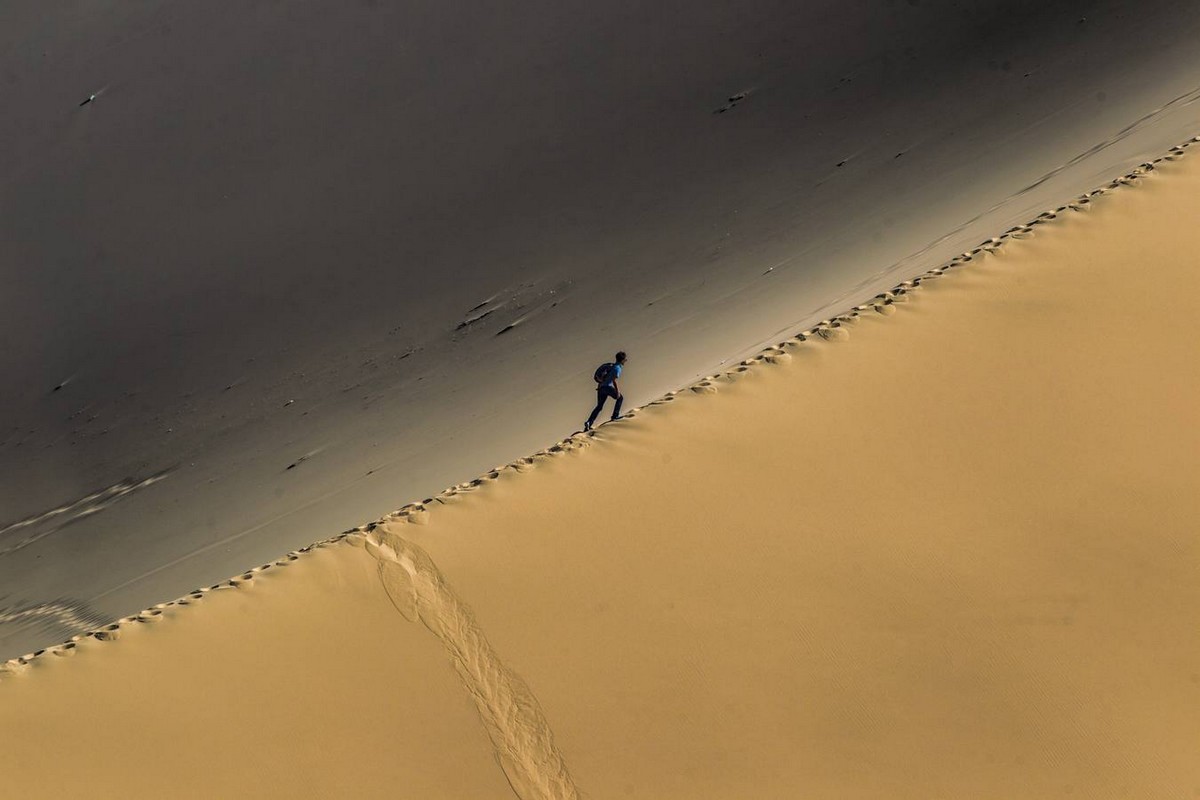 После долгой дороги. Дюны Китая фото. Человек поднимается по пустыне. Путь по песку. Озеро полумесяца в Дуньхуане, Китай.