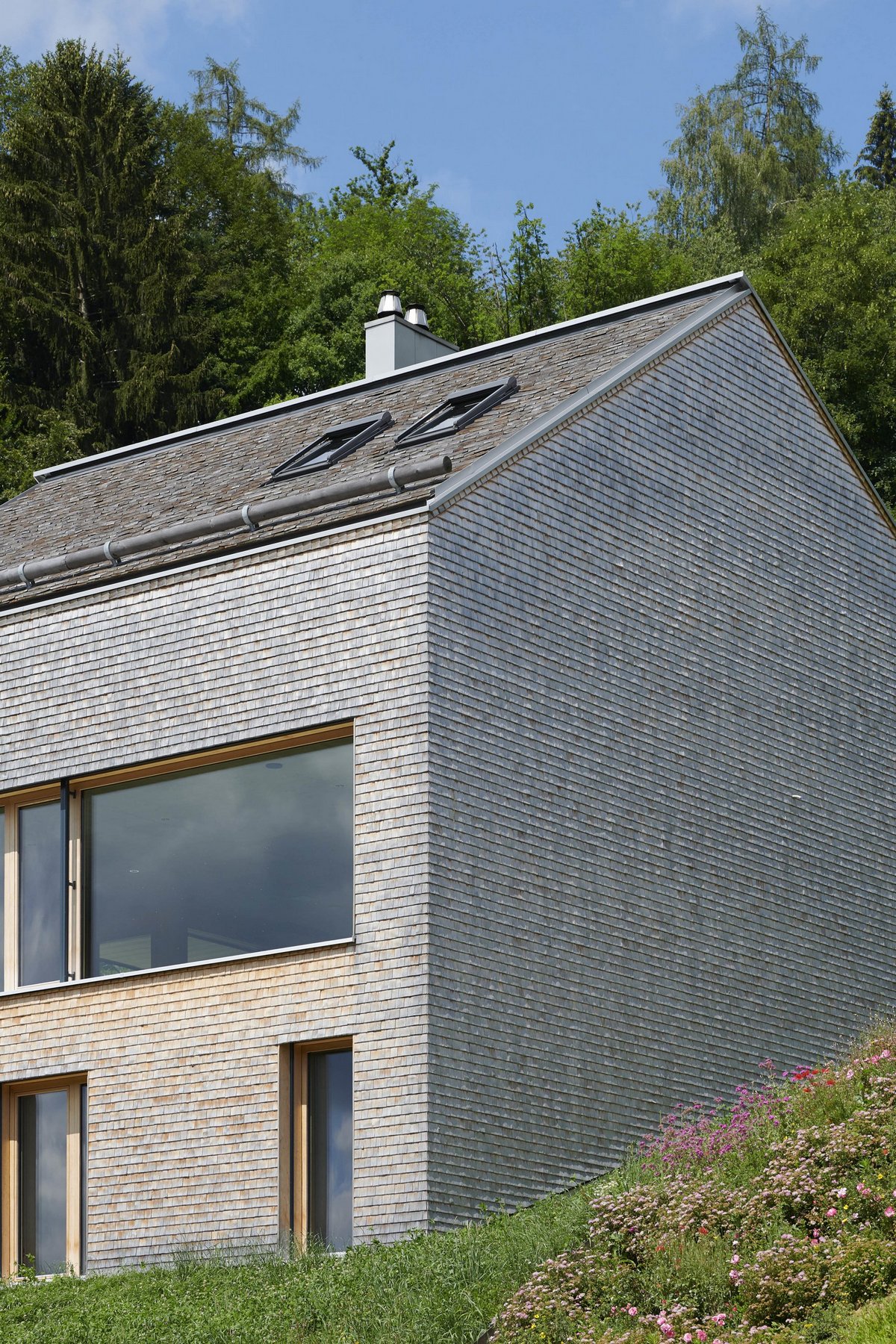 Семейный дом с двухскатной крышей на склоне в Швейцарии