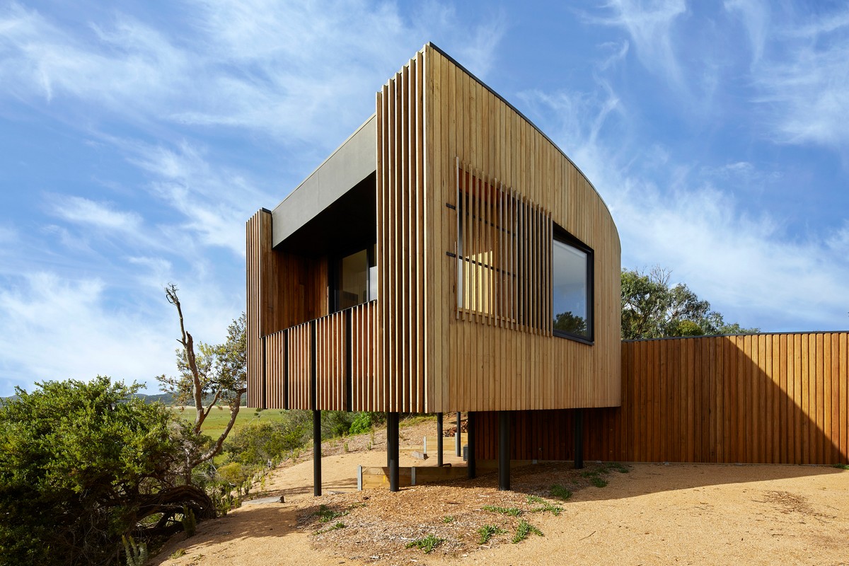 Изогнутый современный дом на гребне песчаной дюны в Австралии