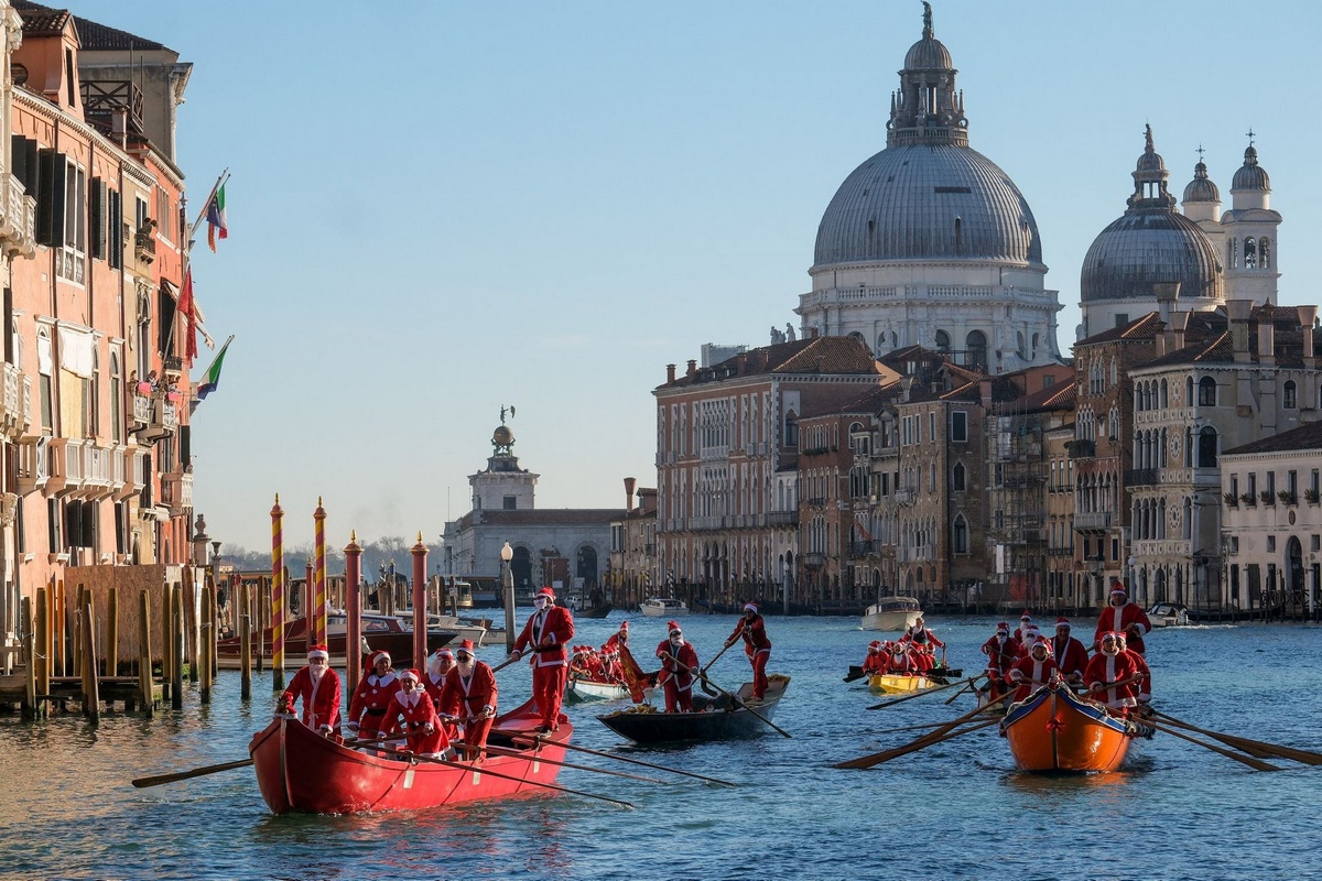 Санта-Клаусы на гондолах во время Рождественской регаты в Венеции