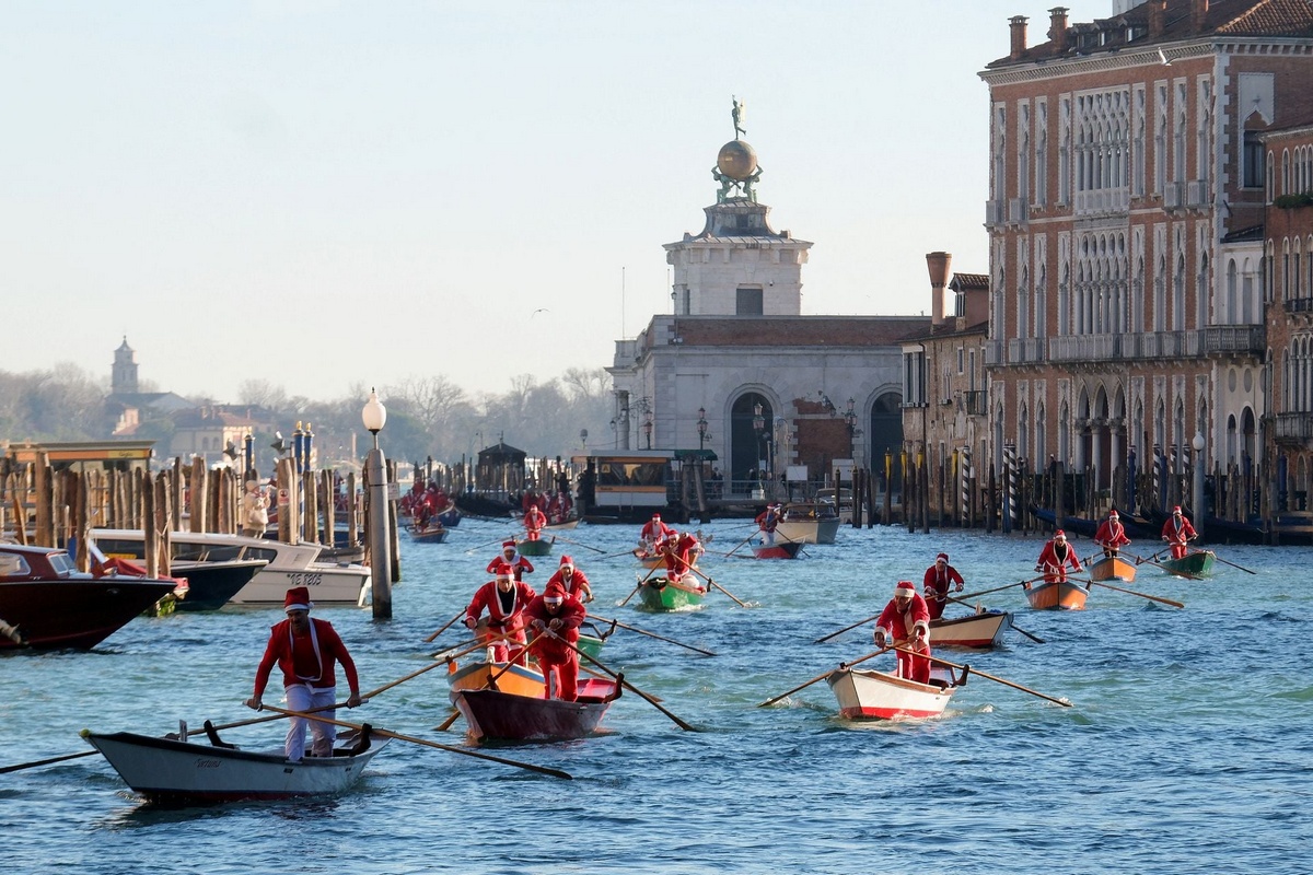 Санта-Клаусы на гондолах во время Рождественской регаты в Венеции
